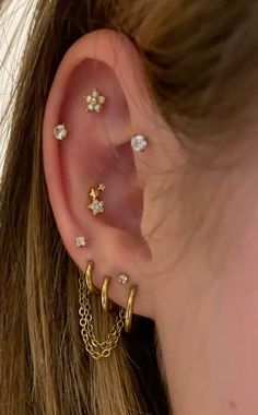 a close up of a person's ear with gold chains and stars on it