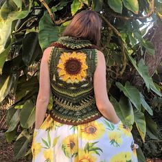 a woman standing in front of a tree with sunflowers on her top and skirt