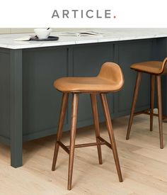 two wooden stools sitting next to each other in a kitchen with gray cabinets and counter tops