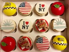 twelve cupcakes in a box decorated with american flags, hot dogs and apple