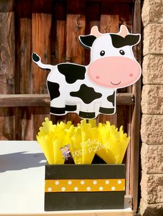 a cow cutout sitting on top of a box filled with flowers