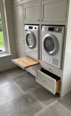 a washer and dryer sitting in a kitchen next to a window with an open drawer