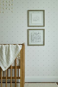 a baby's crib with two pictures on the wall and a blanket draped over it