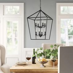 a dining room table with wine glasses on it and a chandelier hanging from the ceiling