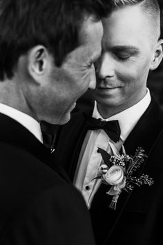 black and white photograph of two men in tuxedos looking at each other's eyes