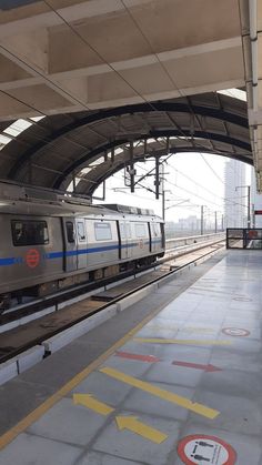 a silver train pulling into a station with no people on the platform or in front of it