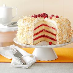 a cake with white frosting and cranberries is on a plate next to a fork