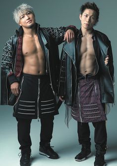 two young men standing next to each other in front of a gray background with no shirt on