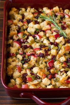 a red casserole dish with stuffing and vegetables