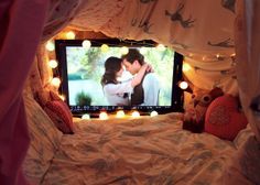 a couple kissing in front of a tv screen with lights on it's sides