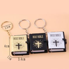 three key chains with bibles on them sitting next to each other