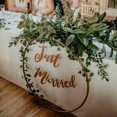 a sign that says just married with greenery on it and two people in the background