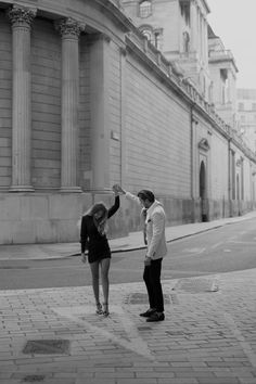 a man and woman standing on the street holding hands