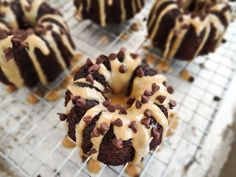 a chocolate bundt cake with frosting and chocolate chips on top, sitting on a cooling rack