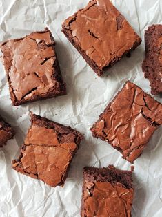 chocolate brownies are sitting on top of white paper and have been cut into squares