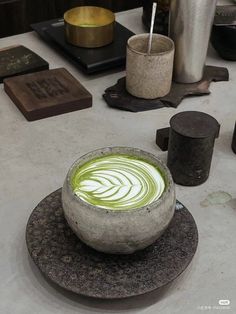 a bowl filled with green liquid sitting on top of a table next to other items