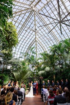 a bride and groom standing at the end of their wedding ceremony under a glass roof