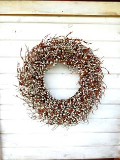 a wreath is hanging on the side of a white building with brown and white flowers