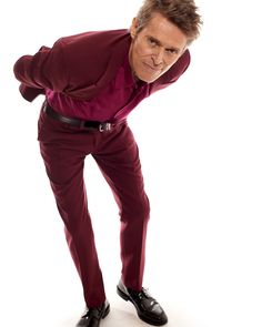 a man in a red suit and black shoes is posing for a magazine cover with his hands on his hips