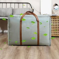 a suitcase sitting on the floor in front of a bed with green leaves painted on it