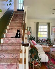 a black and white cat sitting on the stairs in a living room