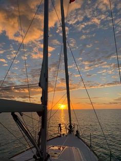 the sun is setting over the ocean on a sailboat