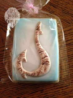 a decorated cookie in the shape of a hook with writing on it sitting on top of a wooden table