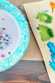 a paper plate that has some paint on it next to a painting tray with watercolors