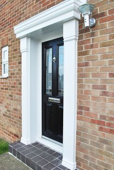 a black front door on a brick building with white trim and glass panels, next to a lamp post