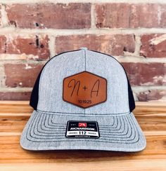 What a great way to celebrate a union, than to outfit the wedding party with hats that feature the lucky couples initials engraved into a top quality product! - Each hat is a top-quality Richardson 112 cap made fresh for you. - 13 Unique Color combos for your hat, including digitally printed camo. - 5 Different high quality leatherette patch options, made from premium materials. Ordering Instructions - In order to keep all information correct, please add each hat separately. - Select the hat col Adjustable Black Hat For Graduation, Black Adjustable Hat For Graduation, Wedding Snapback Trucker Hat, Adjustable Trucker Hat For Wedding, Custom Adjustable Wedding Hats, Wedding Hat With Flat Brim, Adjustable Size Flat Brim Hat For Weddings, One Size Flat Brim Hat For Weddings, Adjustable Hats For Graduation