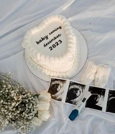 a white cake sitting on top of a table next to flowers and pictures with baby's breath written on it