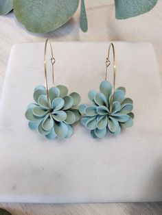 small blue flower earrings sitting on top of a white surface