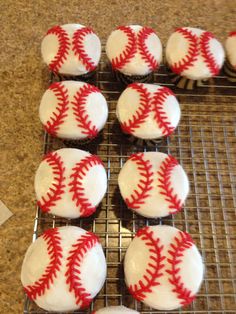 cupcakes with white frosting and red stitches are arranged on a cooling rack