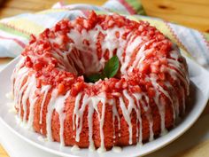 a bundt cake with white icing and strawberries on top sits on a plate