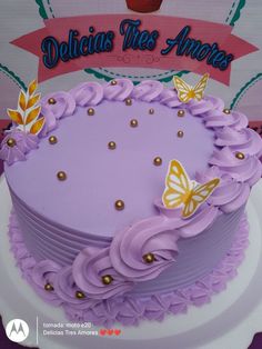 there is a purple cake with gold decorations on the top and butterflies on the side