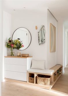 a white room with a bench, mirror and flowers on the wall in front of it