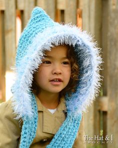 a young boy wearing a blue knitted hat and scarf with a hood on his head