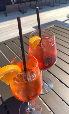 two glasses filled with drinks sitting on top of a table