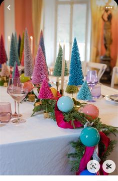 the table is decorated with christmas trees and balls for decoration, including candles on each side