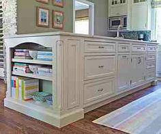 a large kitchen with white cabinets and drawers in the center, along with an area rug on the floor