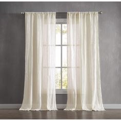 a window with sheer curtains in front of it and a wooden floor next to it