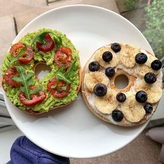 two bagels with toppings are on a white plate