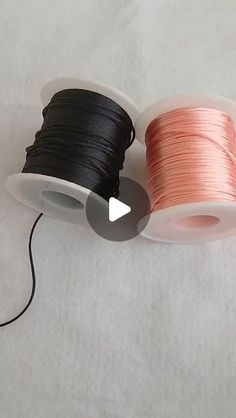 two spools of black and pink thread on a white surface