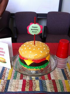 a birthday cake that is sitting on a glass plate with a happy birthday sign next to it