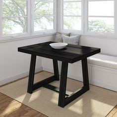 a black table with a bowl on it in front of two windows and a bench