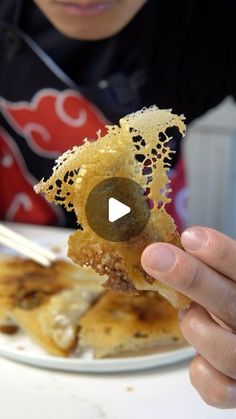 a person is holding up food on a plate with chopsticks in front of them