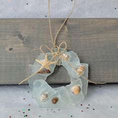 a sea glass wreath with seashells and starfish hanging on a piece of wood