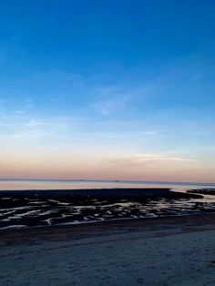 the sky is very blue and there are waves in the water on the beach at sunset