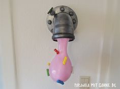 a pink object hanging from the side of a white wall next to a light switch