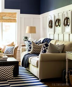 a living room filled with furniture and pillows on top of a striped rug in front of a window